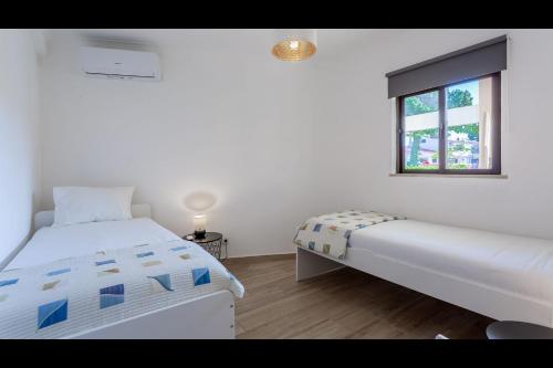 1 Schlafzimmer mit 2 Betten und einem Fenster in der Unterkunft Falésia Modern Flat W/Balcony & Pool by LovelyStay in Albufeira