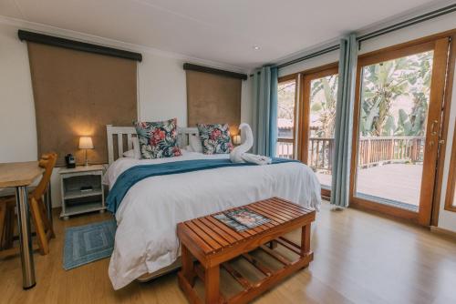 a bedroom with a bed and a desk and a window at Beetleloop Guest House in Nelspruit