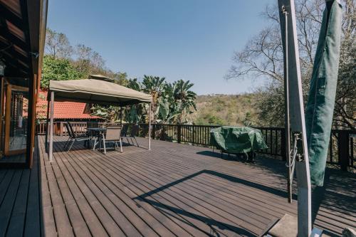 a wooden deck with a table and an umbrella at Beetleloop Guest House in Nelspruit