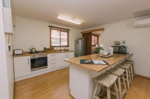 a kitchen with white cabinets and a large island with bar stools at Beetleloop Guest House in Nelspruit