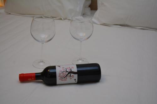 a bottle of wine on a table with three glasses at Eco Paralia in Paralia Katerinis