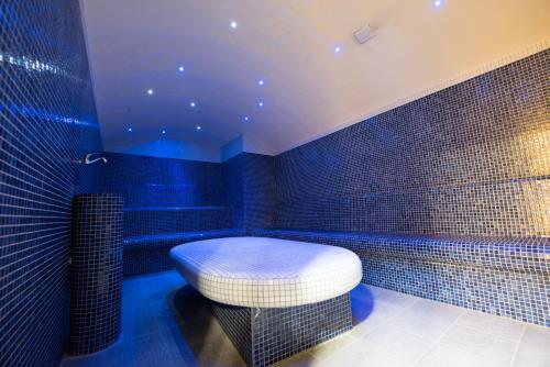 Baño de azulejos azules con taburete y bañera en Hotel Europe en Sarajevo