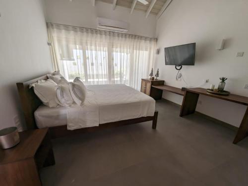 a bedroom with a white bed and a television at AJ Villa in Negombo