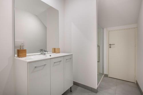 une salle de bain blanche avec un lavabo et un miroir dans l'établissement Séjour apaisant pour 6 au Pouliguen, au Pouliguen