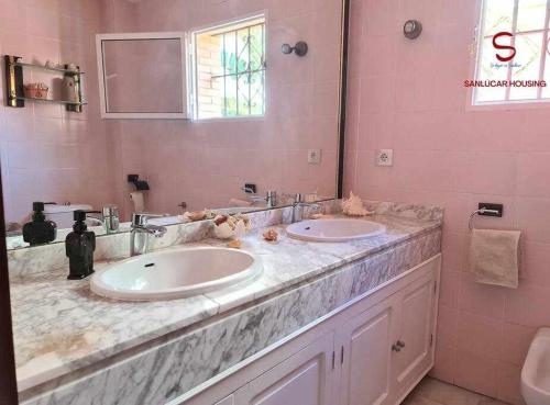 a bathroom with two sinks and a large mirror at Casa Hermosilla céntrica con piscina y jardín in Sanlúcar de Barrameda