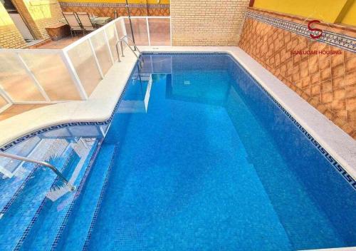 a large swimming pool with blue water at Casa Hermosilla céntrica con piscina y jardín in Sanlúcar de Barrameda