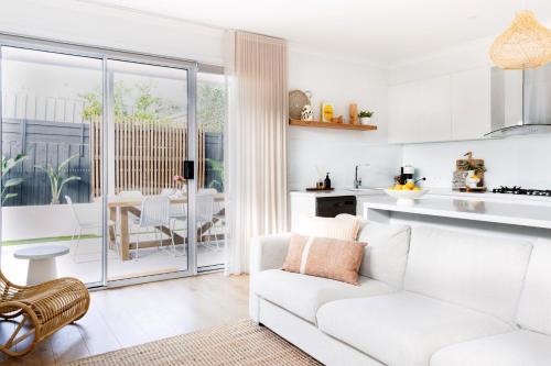 a living room with a white couch and a kitchen at Rosebay - Coastal Holiday Home in Rosebud