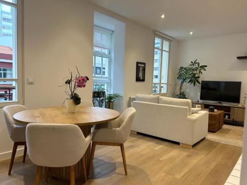 sala de estar con mesa, sillas y TV en CoruñaFlat Apartamentos con encanto en el centro de A Coruña, en A Coruña