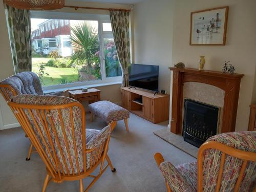 a living room with a fireplace and chairs and a television at Seair in Rustington