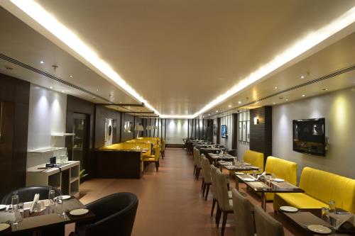 un ristorante con tavoli lunghi e sedie gialle di The Central Park a Rourkela