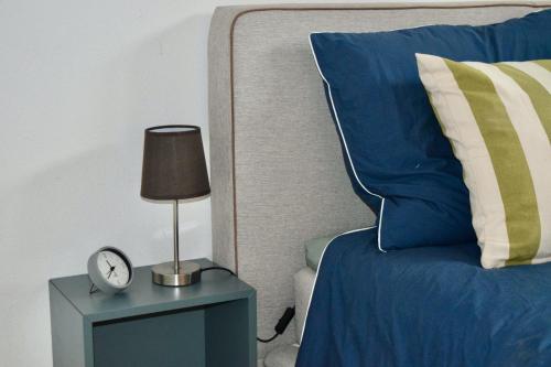 a bed with a blue pillow and a clock on a night stand at Bed and Bike Rheine in Rheine