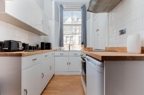 uma cozinha com armários brancos e uma bancada em Bright & Homely City Centre Apartment near Holyrood em Edimburgo