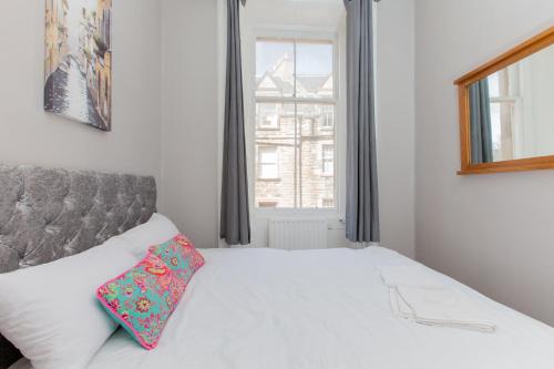 a bedroom with a white bed with a pillow on it at Bright & Homely City Centre Apartment near Holyrood in Edinburgh