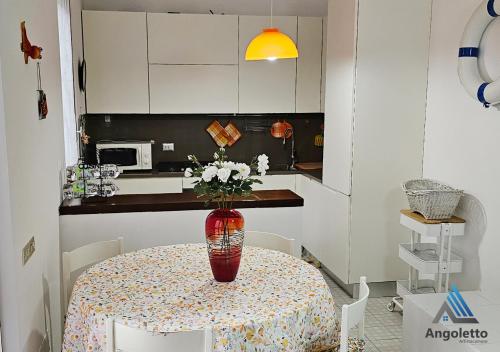 a kitchen with a table with a vase of flowers on it at Angoletto Sirolo Affittacamere in Sirolo