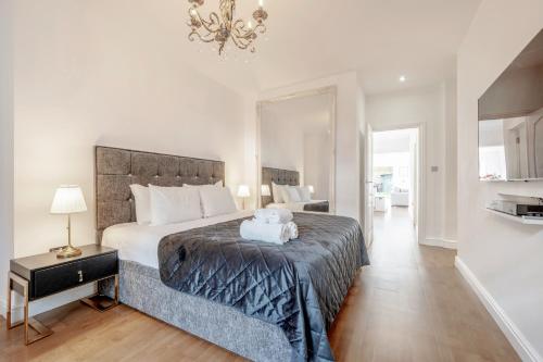 a bedroom with a large bed and a chandelier at Maida Vale Gem by Little Venice with Stunning Garden in London