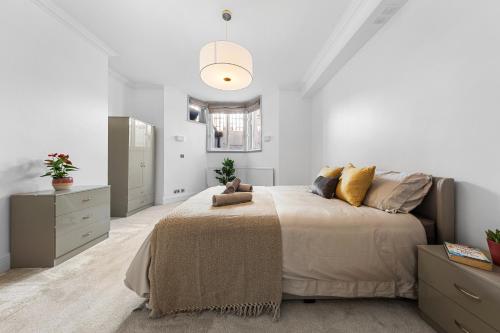 een witte slaapkamer met een groot bed en een spiegel bij Harrods 2 Bed Lux Flat w/patio in Londen