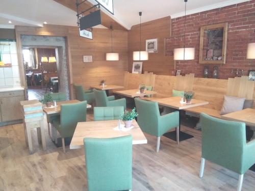 a restaurant with wooden tables and green chairs at Landgasthof Santner in Thalgau