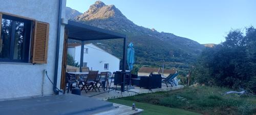 ein Haus mit einer Terrasse mit einem Tisch und Stühlen in der Unterkunft Maison neuve Vue imprenable Piscine et spa in Calenzana