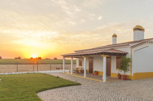 a house with the sunset in the background at Agro-Turismo do ROXO in Santa Vitória