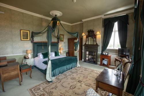 a bedroom with a canopy bed and a fireplace at Grafton Manor Hotel in Bromsgrove