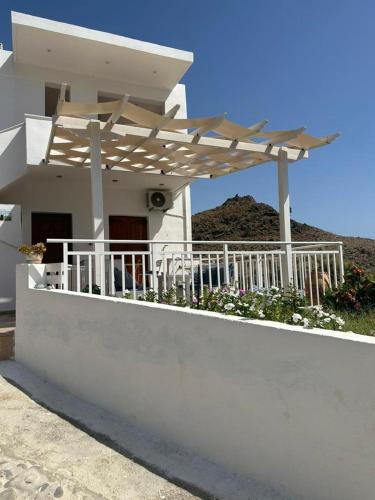 a white house with a porch with a wooden pergola at Panorama Zimmer und Apartments Lentas in Léntas