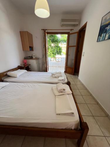 a room with three beds and a door to a patio at Panorama Zimmer und Apartments Lentas in Léntas