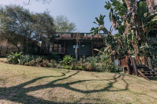 a tree shadows on the grass in front of a house at Beetleloop Guest House in Nelspruit