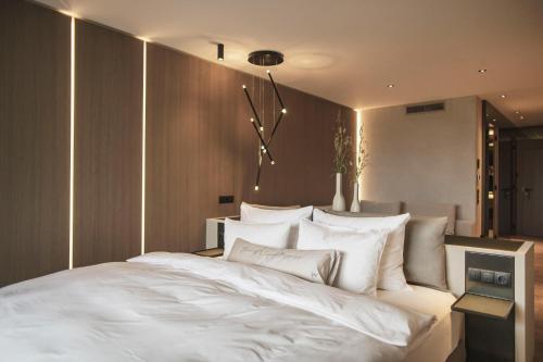 una camera da letto con un grande letto bianco con cuscini bianchi di Hotel Lanerhof active/spa/balance a San Lorenzo di Sebato
