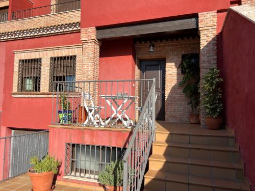 czerwony budynek z balkonem z roślinami w obiekcie Casa grande de tres plantas w mieście Linares