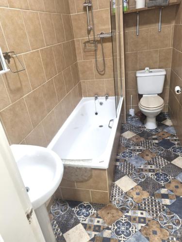 a bathroom with a tub and a toilet and a sink at 2 Beach House in Bridlington