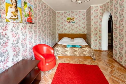 a bedroom with a bed and a red chair and a red rug at Киев in Petropavlovsk
