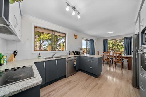 eine Küche mit grauen Schränken und einem Esszimmer in der Unterkunft Cozy holiday plant house ,close to CBD and Beach in Kingston