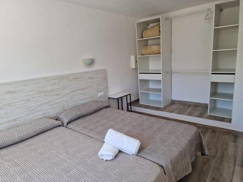 1 dormitorio con 1 cama y estanterías con pan en Aparthotel Puerto Cala Vadella en Cala Vadella