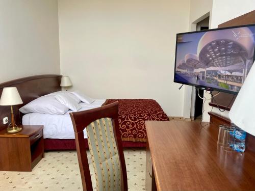 a hotel room with a bed and a flat screen tv at Gościniec Uniejów in Uniejow