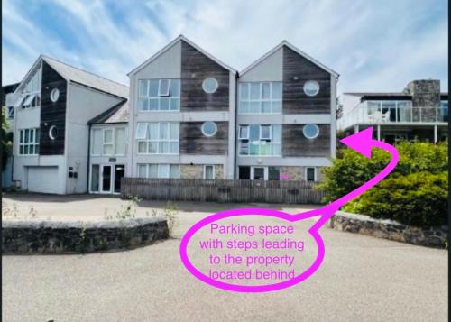 a house with a pink sign in front of it at Above the Bay - Enclosed garden apartment with parking in Penzance