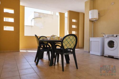 une salle à manger avec une table et des chaises ainsi qu'un lave-linge dans l'établissement Appartamento Fontana Greca 4 ,Gallipoli, à Gallipoli