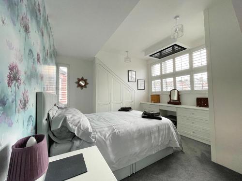 a white bedroom with a bed and a desk at Lovely Comfortable 3BR Property in Nether Edge