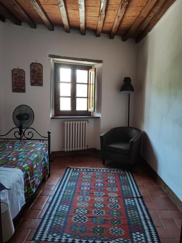 a bedroom with a bed and a chair and a rug at Short Rent Il Casale in Capolona