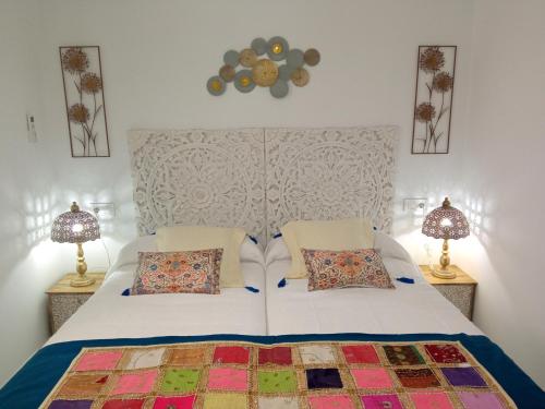 1 dormitorio con 1 cama blanca y 2 lámparas en Los encantos de Almavir, en Córdoba