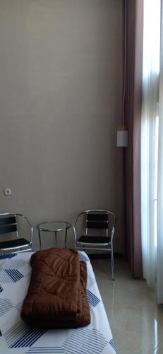 a bedroom with a bed and two chairs and a window at Home Stay Syariah Omahku in Tlekung