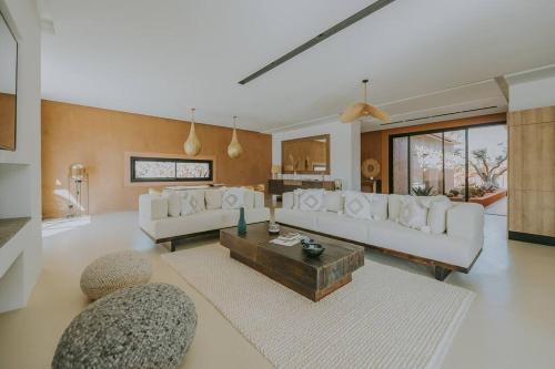 una sala de estar con sofás blancos y una mesa. en Villa 3 chambres Piscine - Golf, en Marrakech