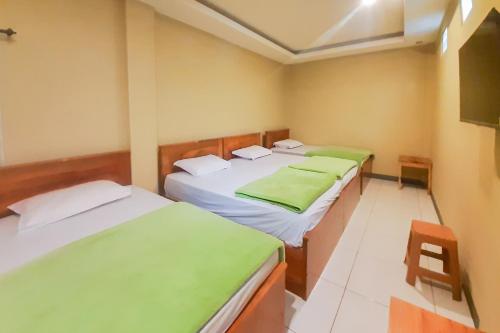 - une chambre avec 2 lits avec des draps verts et une chaise dans l'établissement Delvia Bromo Homestay Mitra RedDoorz, à Pasuruan