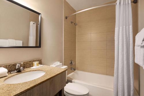 a bathroom with a sink and a toilet and a tub at Days Inn by Wyndham Miami Airport North in Miami