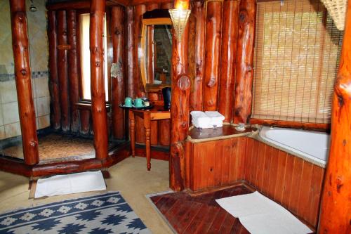 a wooden bathroom with a tub and a mirror at Hartbeespoortdam Lodge in Hartbeespoort