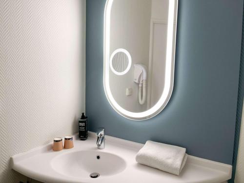 een badkamer met een witte wastafel en een spiegel bij ibis Martigues Centre in Martigues