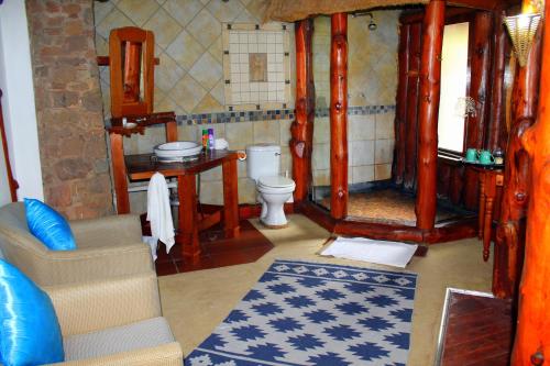 a bathroom with a toilet and a couch in a room at Hartbeespoortdam Lodge in Hartbeespoort