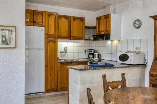 a kitchen with wooden cabinets and a white refrigerator at Art- Apartamentos Revilla Tacke H in Empuriabrava