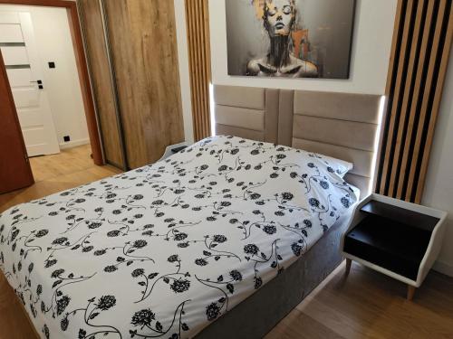 1 dormitorio con 1 cama con edredón blanco y negro en Apartament Loft, en Toruń
