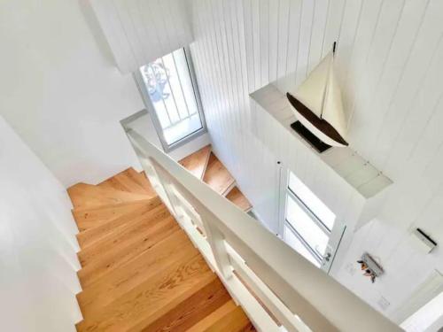 escalera blanca en una habitación con ventana en La villa des Dunes - 80m de la plage/paddle/vélos, en Fouesnant