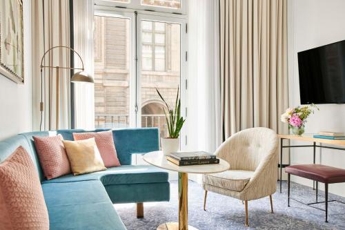 uma sala de estar com um sofá azul e uma mesa em Hôtel du Louvre, in The Unbound Collection by Hyatt em Paris